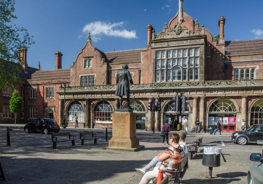 View of people sat on benches outside of Stoke railway station.