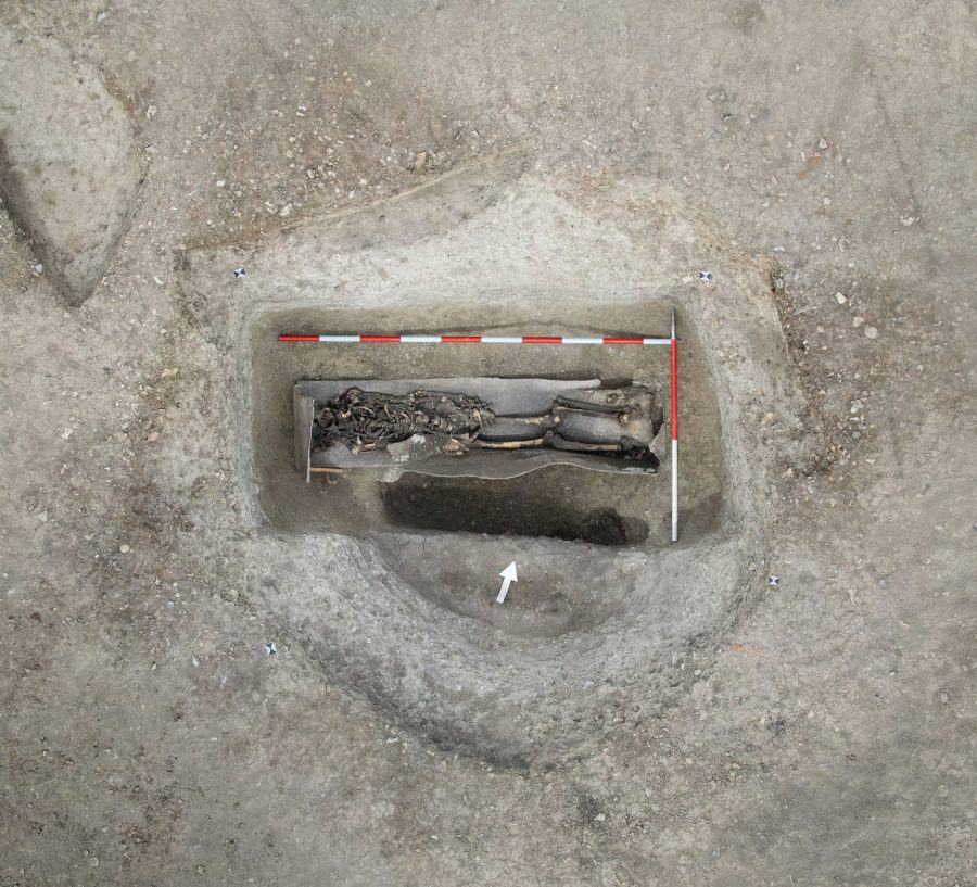Archaeological excavation revealing a skeleton in a lead coffin, horizontal view.