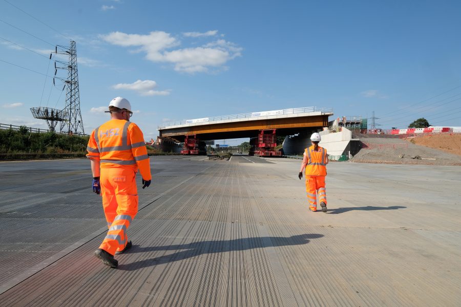 Construction workers view the move of a large bridge into place over a motorway. It will provide improved access to Interchange station.
