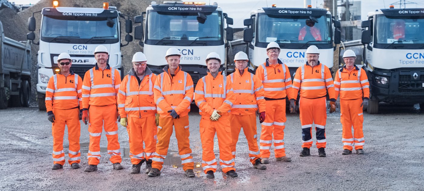 Team of people standing in front of heavy goods vehicles