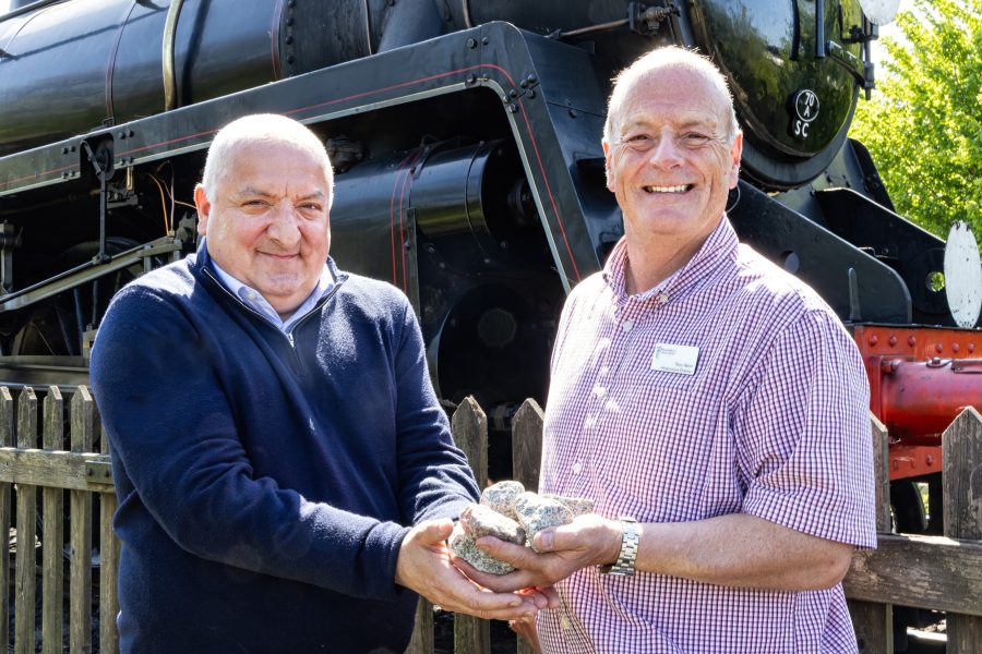 Bluebell Railways pose holding the donated ballast in front of a steam train.